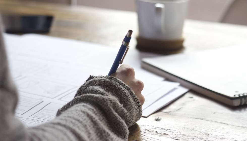 Person writing in a dream journal beside their bed at dawn