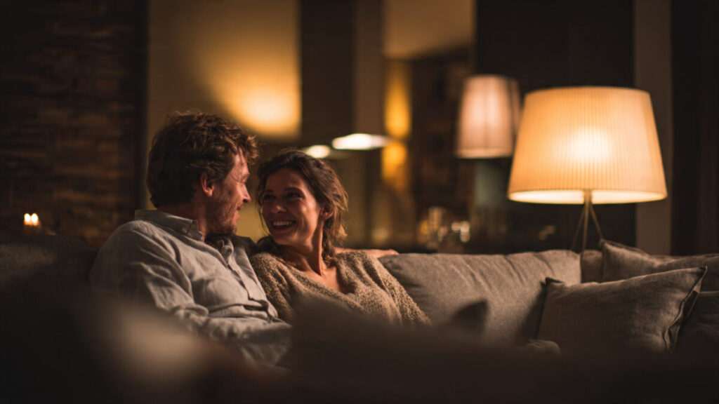 Happy couple talking on a sofa, demonstrating healthy communication and soulmate alignment