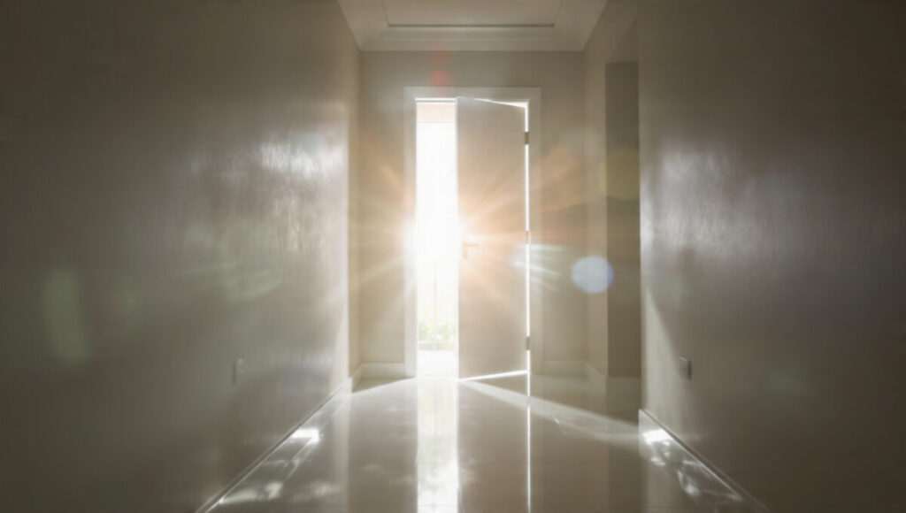 An open door filled with bright light symbolizing the energy shift of the First Quarter Moon.
